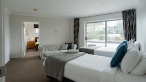 Habitación de hotel con dos camas, un sofá, una ventana con cortinas y vistas al exterior.