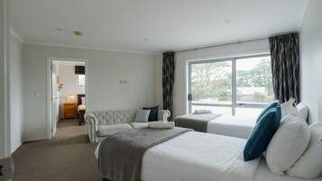 Habitación de hotel con dos camas, un sofá, una ventana con cortinas y vistas al exterior.