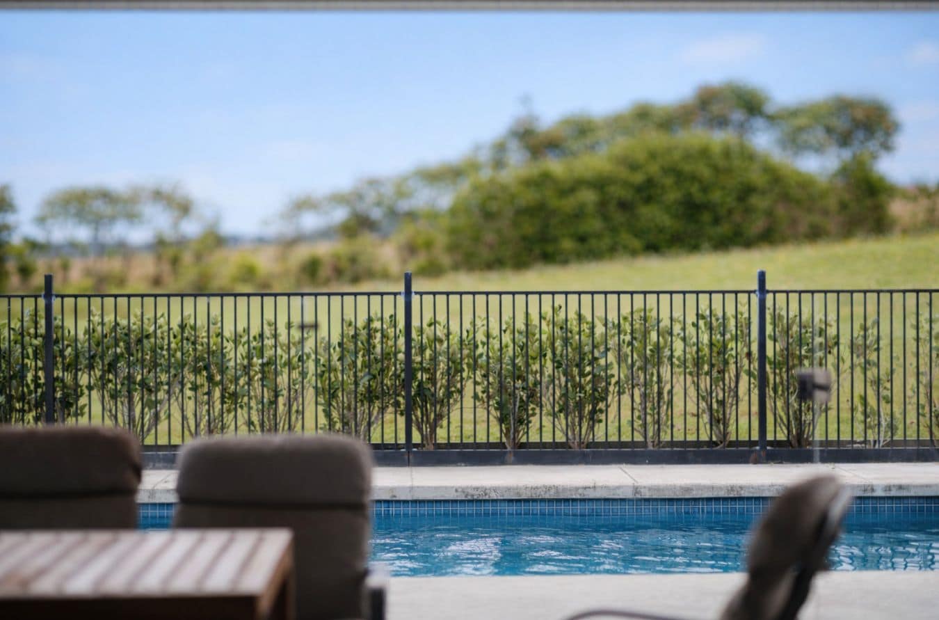 Un espace piscine donnant sur un jardin clos et des arbres.
