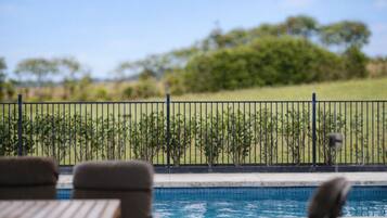 Un espace piscine donnant sur un jardin clos et des arbres.