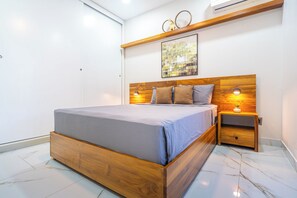 Een moderne slaapkamer met een houten bed, nachtkastje, een wandlamp en een decoratief object boven het bed.