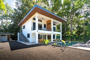 Ein modernes Haus mit zwei Etagen, einem Balkon, einem Schwimmbad und einem gepflegten Garten.