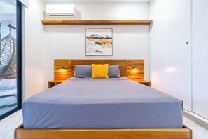 Ein modernes Schlafzimmer mit einem großen Bett, einem hölzernen Kopfteil, Nachttischlampen und einem gerahmten Kunstwerk an der Wand.