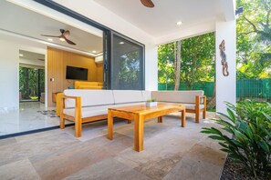 Een moderne woonkamer met een bank, twee houten tafels en een televisie.