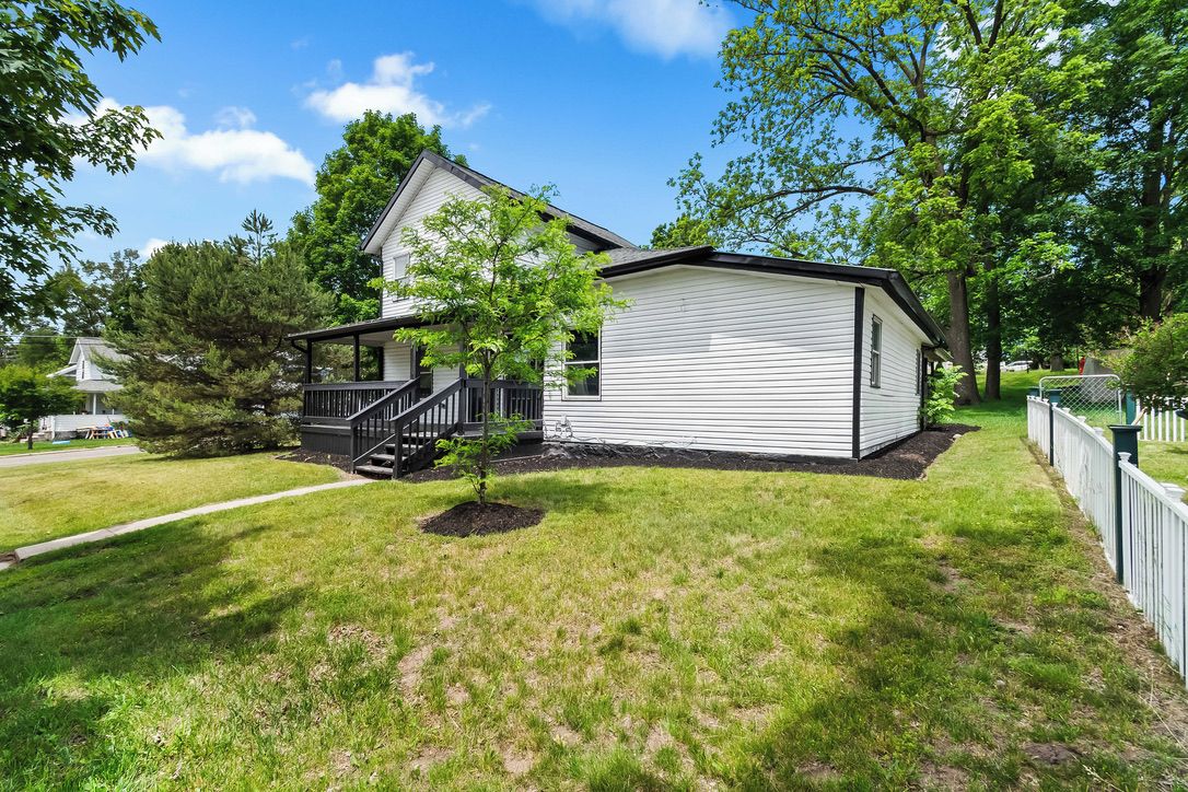A single-story house with a front porch and a small tree in the yard.