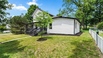 A single-story house with a front porch and a small tree in the yard.