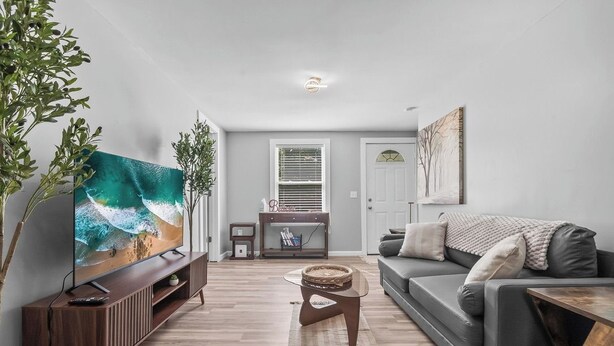 A modern living room with a flat-screen TV, a grey sofa, a coffee table, and a wooden entertainment unit. - The Howder House / Refined 1BR  / Sleeps 4 (Hillsdale)