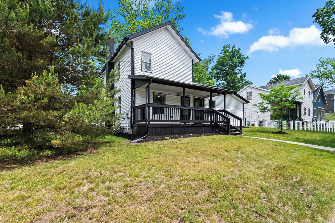 A two-story house with a porch and a small staircase leading to the entrance.