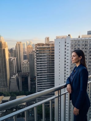 A person standing on a balcony overlooking a cityscape with high-rise buildings. - Makati CBD Executive Skyline Apartments (Makati)