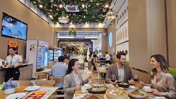 Un restaurante con varias mesas, una variedad de platos, y un techo decorado con flores y luces.