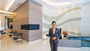 Un vestíbulo moderno con mostrador de recepción, zona de estar y una pared curva con líneas verticales.