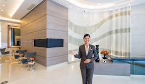 A modern lobby with a reception desk, seating area, and a curved wall with vertical lines. - Makati CBD Executive Skyline Apartments (Makati)