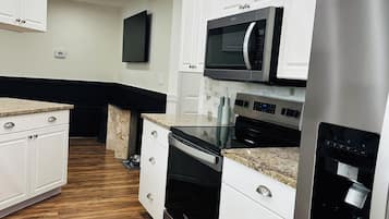 A modern kitchen with white cabinetry, stainless steel appliances, and a granite countertop.