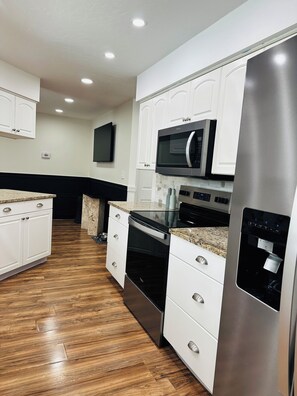 A modern kitchen with white cabinetry, stainless steel appliances, and a granite countertop.