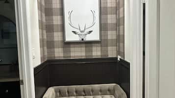 Quarto com sofá estofado, arte com cabeça de veado na parede e painel de azulejos xadrez.
