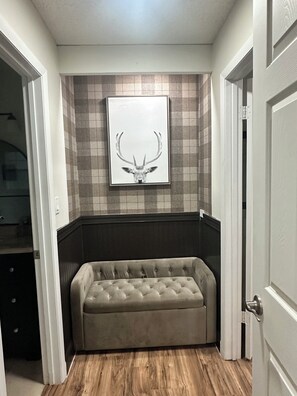 A room with a tufted sofa, a wall-mounted deer head artwork, and a checkered tile backsplash.