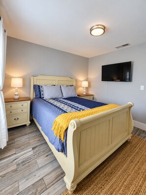 Ein Schlafzimmer mit einem Bett, Nachttischen, einem Flachbildfernseher und einer Deckenleuchte.