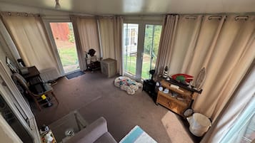 Een woonkamer met een bank, een bijzettafeltje, een ventilator en een raam met gordijnen.