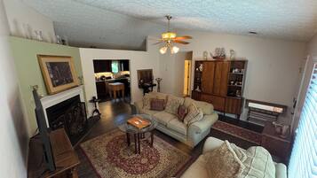 A living room with a sofa, coffee table, fireplace, and a view into the kitchen.