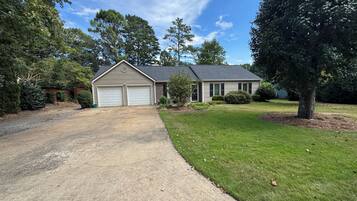 A single-story house with a garage, a front lawn, and a tree.