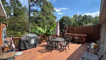 A wooden deck with outdoor furniture, including a table and chairs, and a barbecue grill.