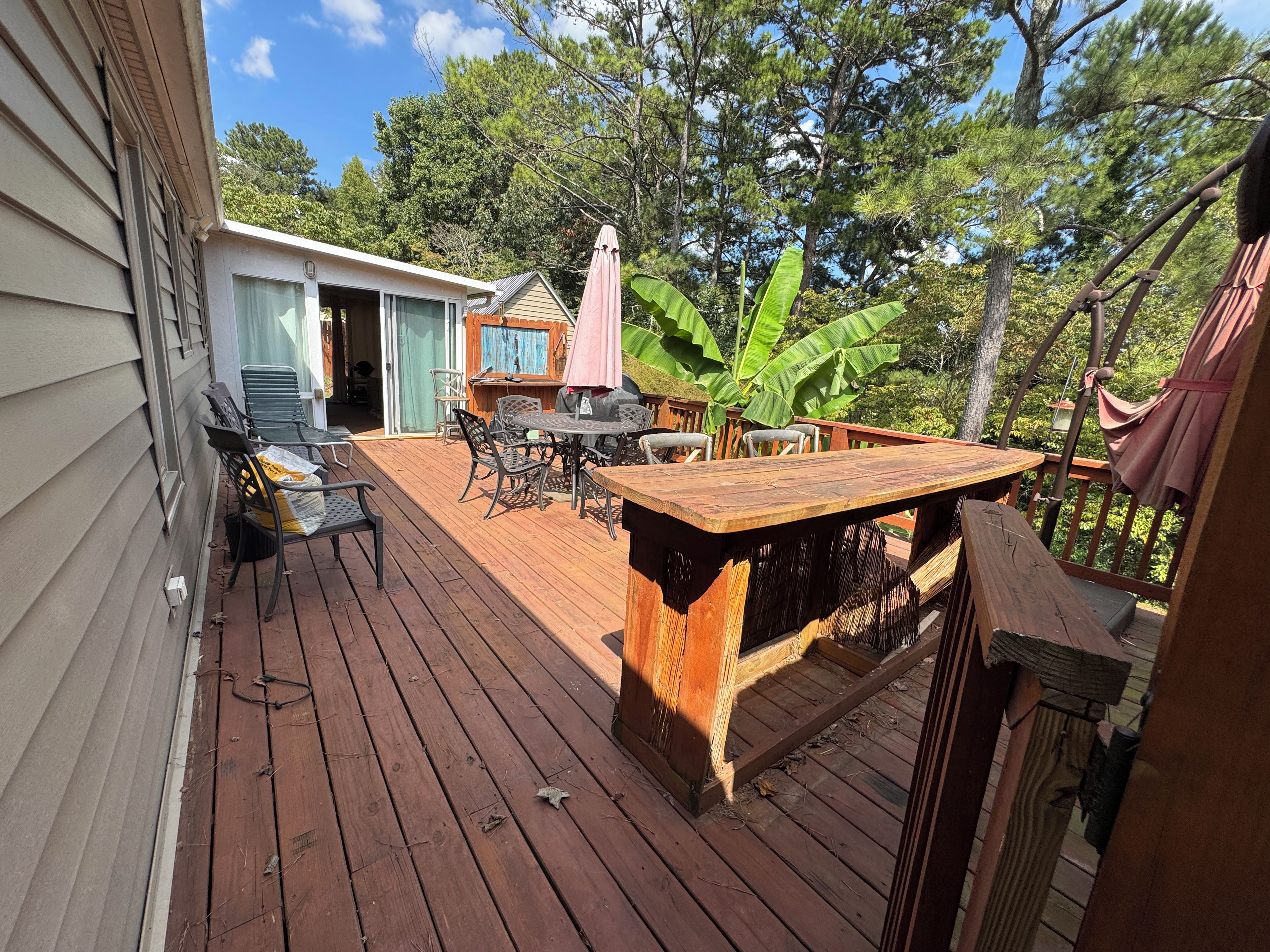 Eine Holzterrasse mit Gartenmöbeln, einem Tisch und Stühlen.