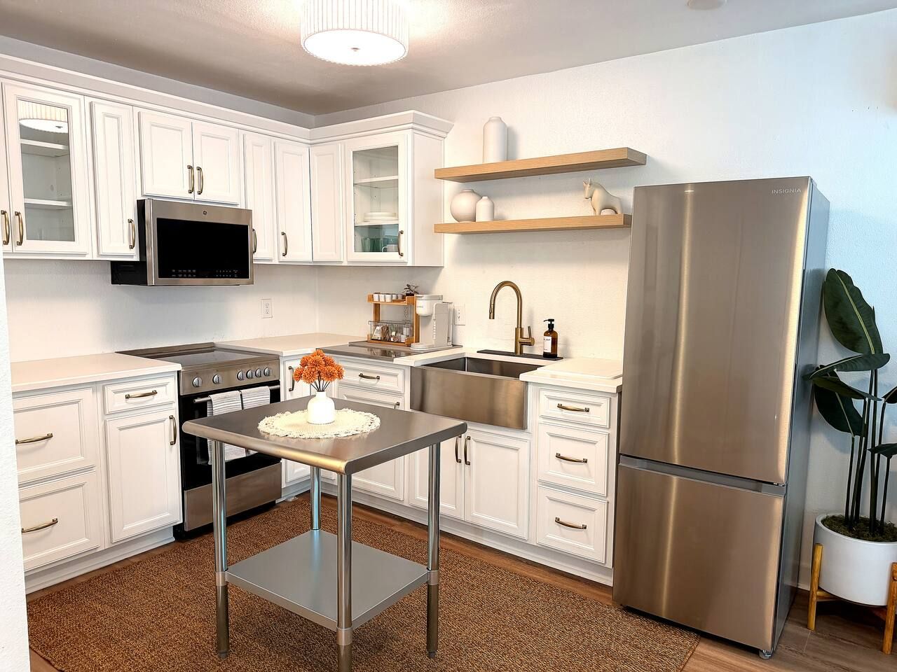 A modern kitchen with white cabinetry, stainless steel appliances, and a central island with a vase of flowers.