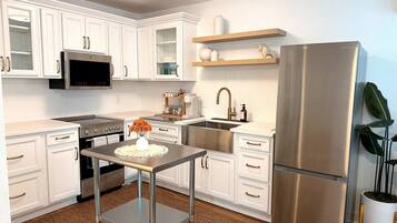 A modern kitchen with white cabinetry, stainless steel appliances, and a central island with a vase of flowers.