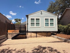 A two-story house with a front porch, a staircase, and a fenced yard. - Nomad & Nest- Renovated Tiny Home in Historic Monte Vista (San Antonio)