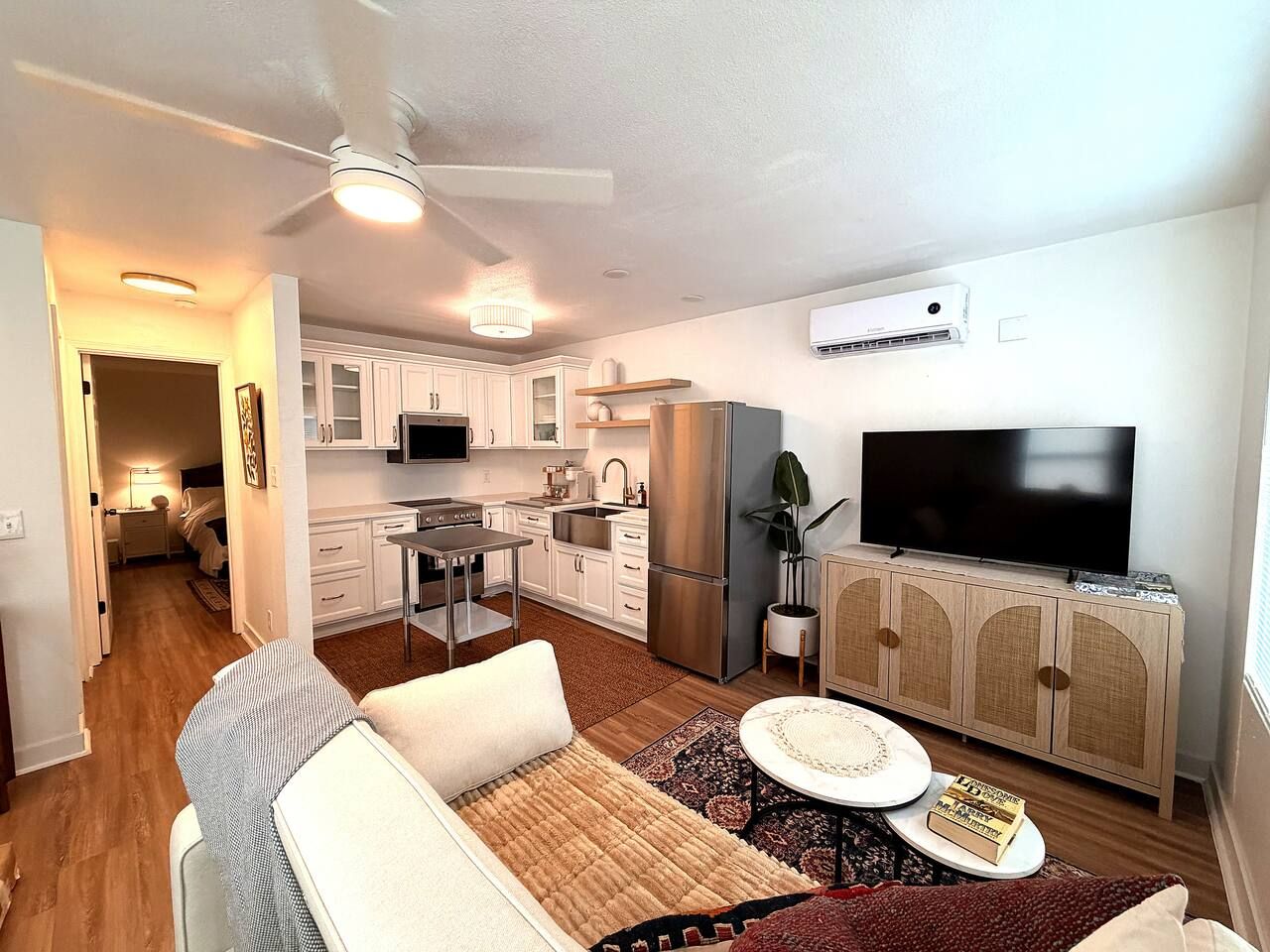 A modern apartment with a kitchen, dining area, living room, and a TV.