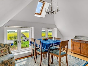 A dining area with a table set for four, a chandelier, and a view of a green field through large windows. - 4 Person Holiday Home in Snedsted (Snedsted)