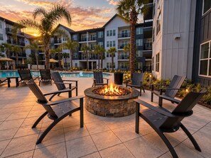 A poolside area with lounge chairs and a fire pit, surrounded by multi-story buildings. - Big Home 3 Beds Balcony Pool View Gym Downtown Jax (Jacksonville)