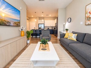 Ein modernes Wohnzimmer mit einem weißen Couchtisch, einem grauen Sofa und einem flachbildfernseher an der Wand.