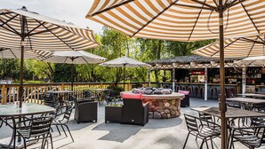 Een terras buiten met gestreepte parasols, een stenen bargedeelte en rieten meubels.