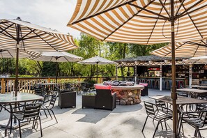 An outdoor patio area with striped umbrellas, stone bar counter, and wicker furniture. - Lakeview Condo with Private Balcony by Bigfork Bay (Bigfork)