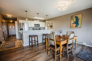 A modern kitchen with white cabinets, a central island, and pendant lighting. - Lakeview Condo with Private Balcony by Bigfork Bay (Bigfork)