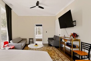 A hotel room with a bed, two sofas, a coffee table, a TV, and a desk with a chair.