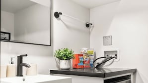 Un baño moderno con lavamanos, espejo y lavadora.