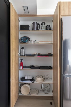 A kitchen with wooden cabinets, a stainless steel refrigerator, and various kitchen appliances and utensils.