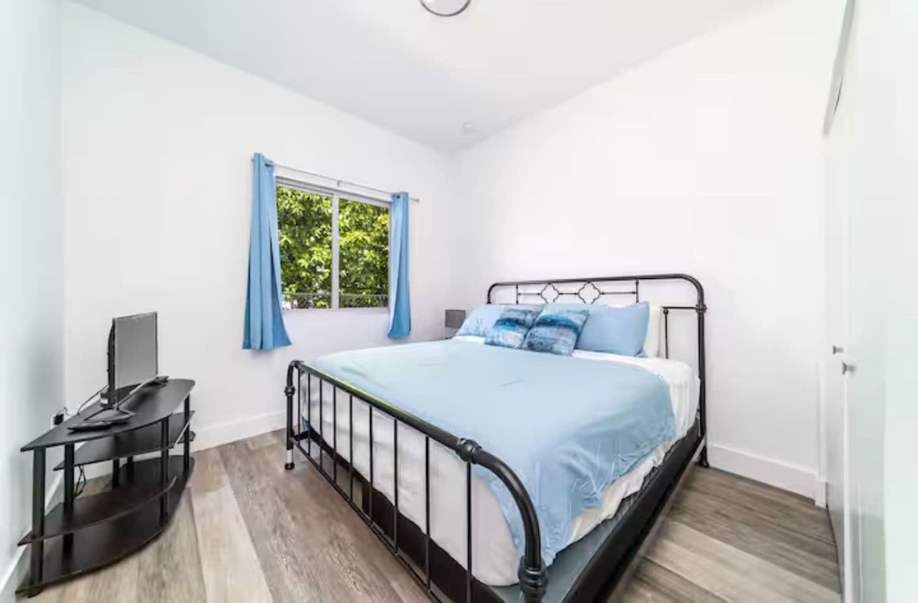 Quarto com cama, escrivaninha e janela.