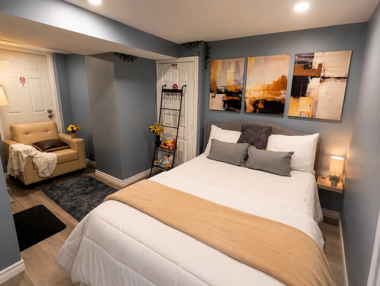Quarto com cama, mesas de cabeceira, uma cadeira e obras de arte na parede.