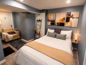 A bedroom with a bed, bedside tables, a chair, and artwork on the wall.