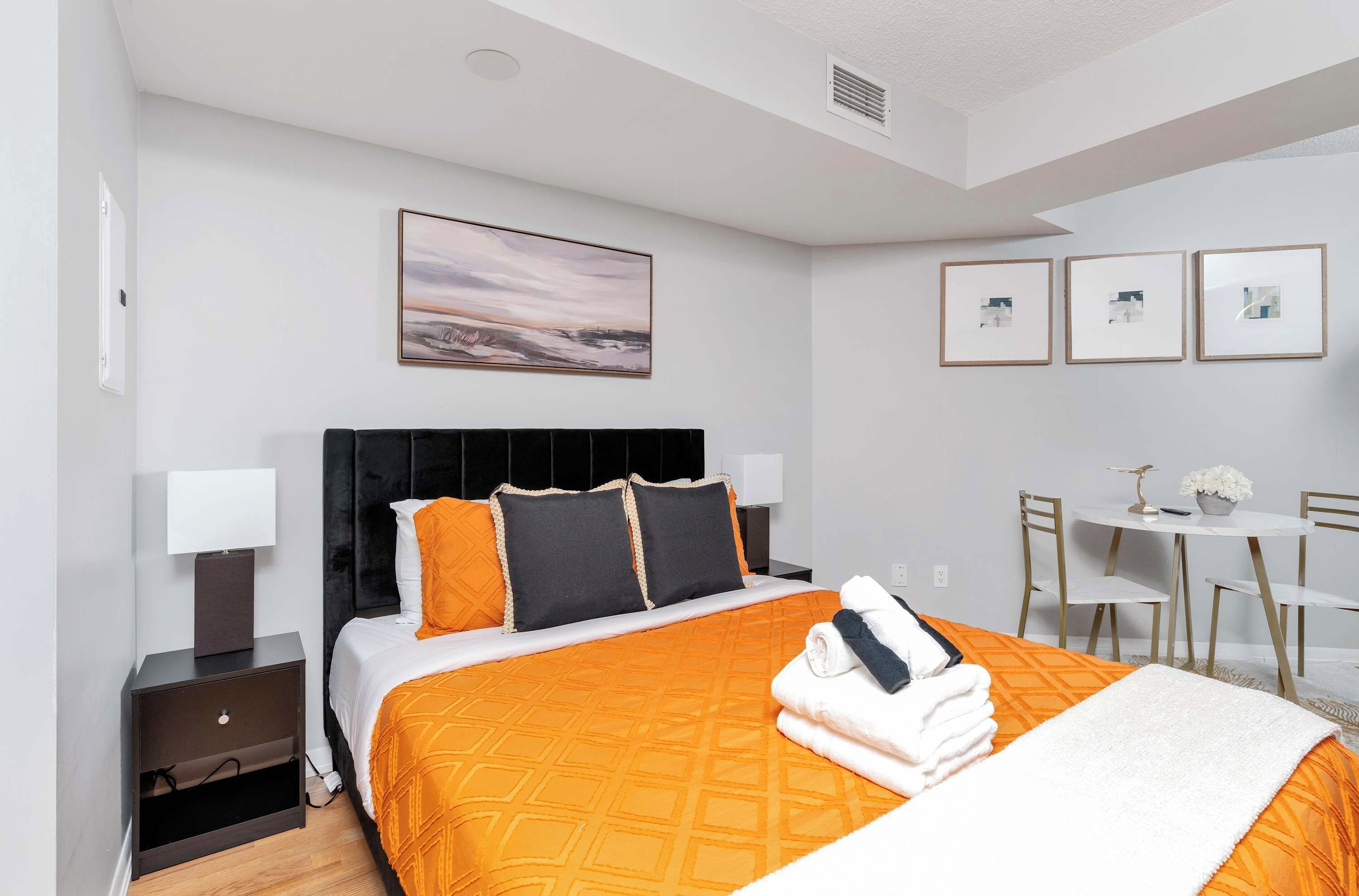 A hotel room with a bed, bedside tables, a desk, and chairs.