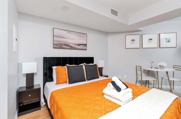 A hotel room with a bed, bedside tables, a desk, and chairs. - Chic Waterfront Studio Steps to DT Toronto (Toronto)