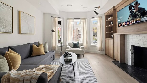 Una sala moderna con sofá, sillón, mesa de centro y chimenea.