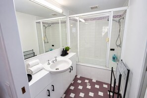 A bathroom with a white sink, mirror, and shower.