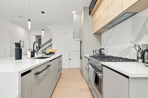 Eine moderne Küche mit einer zentralen Kochinsel, Edelstahlgeräten und einer Marmor-Spritzschutzwand.