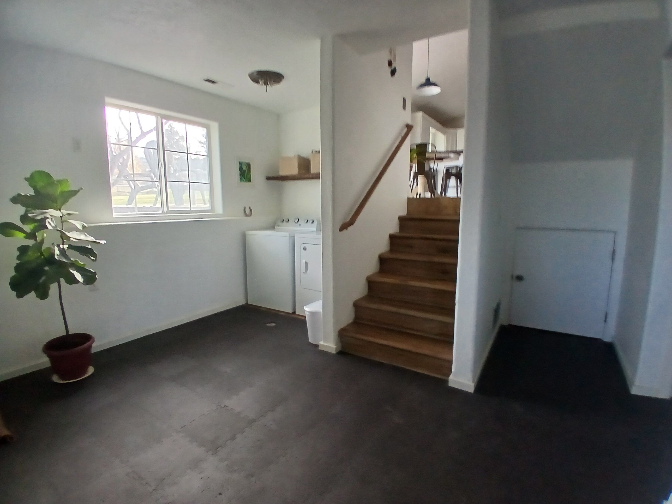 A laundry room with a washing machine, dryer, and a staircase leading to another level.