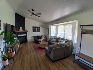 A living room with a sofa, a coffee table, a TV, and a ceiling fan.