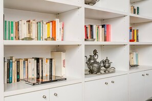 A bookshelf with various books and a decorative metal tea set. - 3 Bedroom, 3 bathrooms Quiet Flat + Cable Internet (Milano)